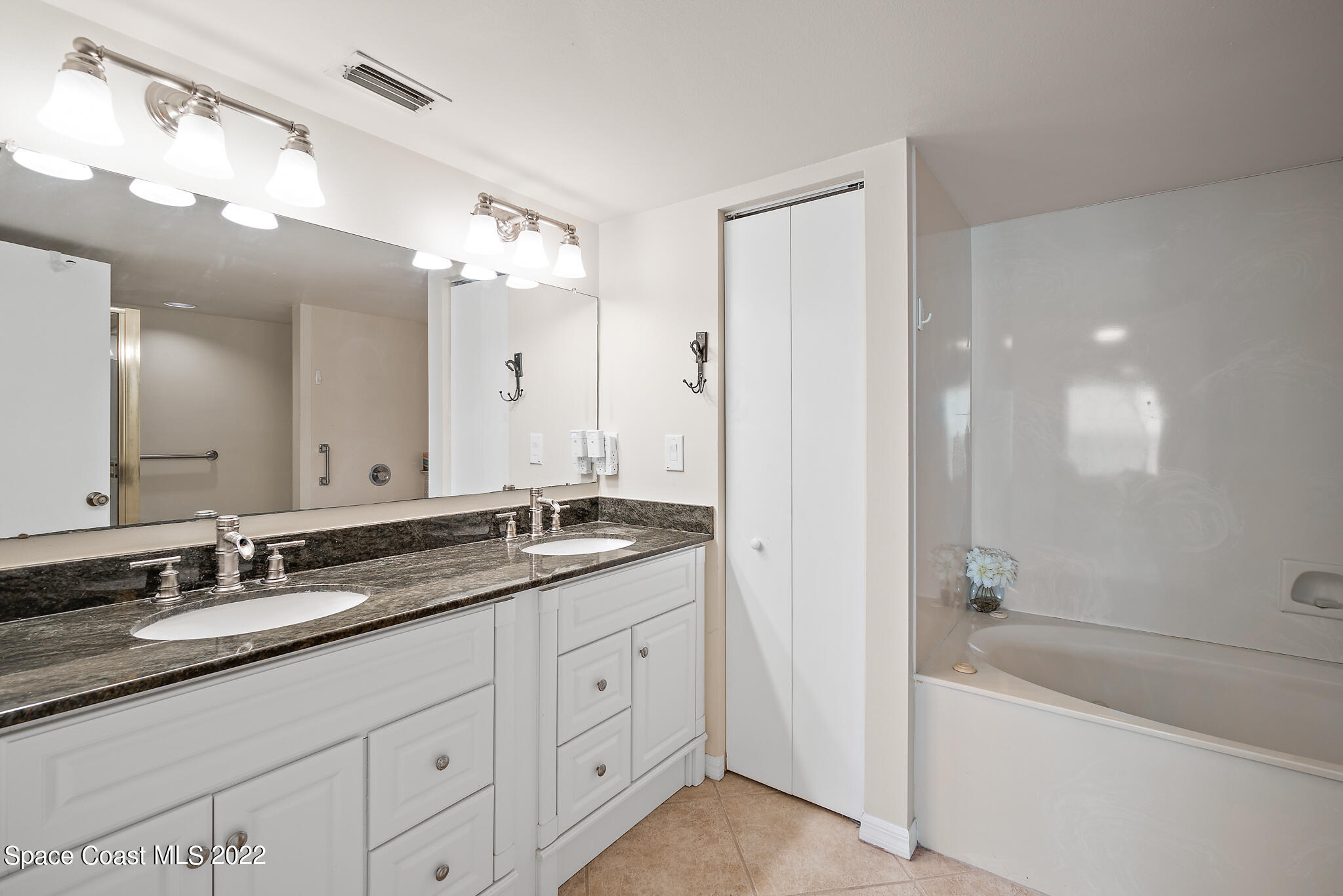 6770 Ridgewood Avenue, Unit 502 Cocoa Beach, FL 32931 - Photo 12 of 25 a bathroom with a granite countertop double vanity sink a mirror and a bathtub