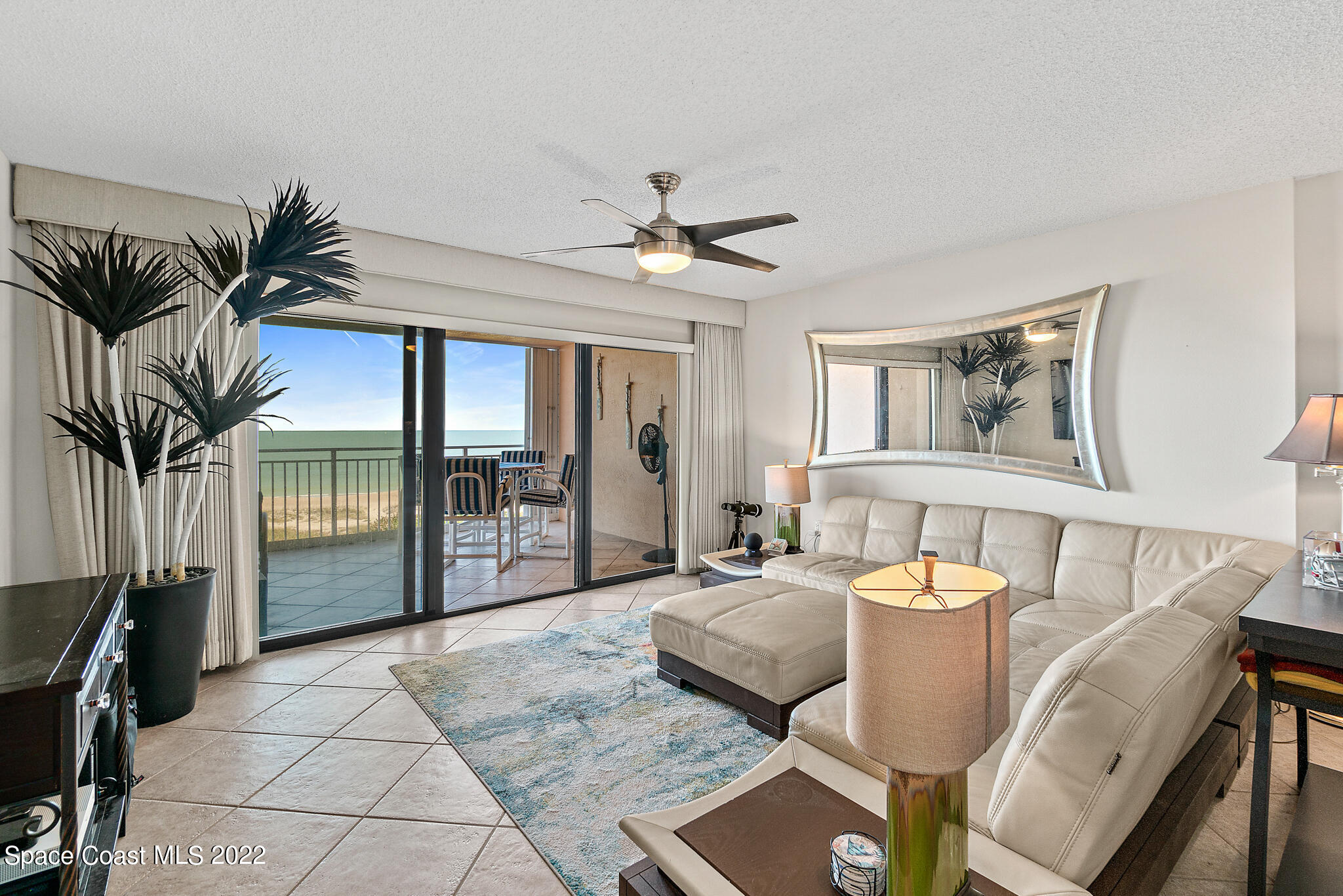 6770 Ridgewood Avenue, Unit 502 Cocoa Beach, FL 32931 - Photo 4 of 25 a living room with furniture a flat screen tv and a large window