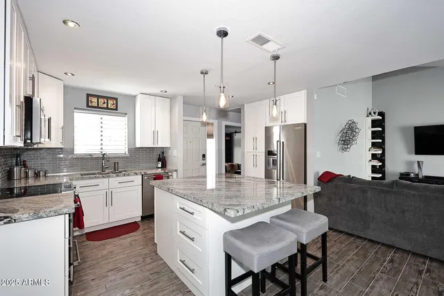 a kitchen with a stove a refrigerator a sink and chairs