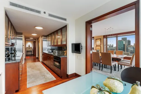 a kitchen with stainless steel appliances kitchen island granite countertop a refrigerator a stove top oven a dining table and chairs with wooden floor