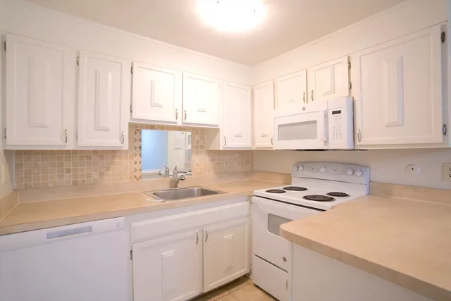 a kitchen with cabinets appliances a sink and a window