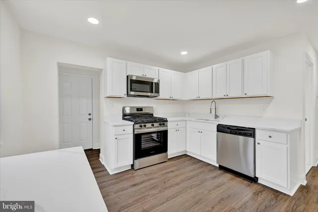 a kitchen with cabinets stainless steel appliances and wooden floor