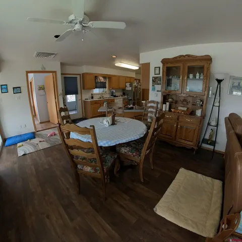 a large kitchen with stainless steel appliances granite countertop a stove top oven a sink a dining table and chairs with wooden floor