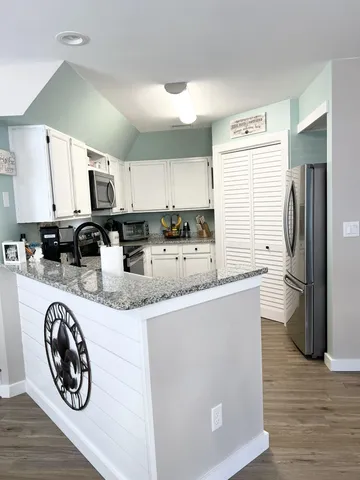 a kitchen with stainless steel appliances granite countertop a stove a sink and white cabinets