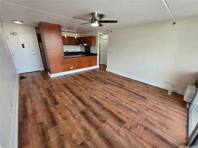 a view of empty room with wooden floor and fan