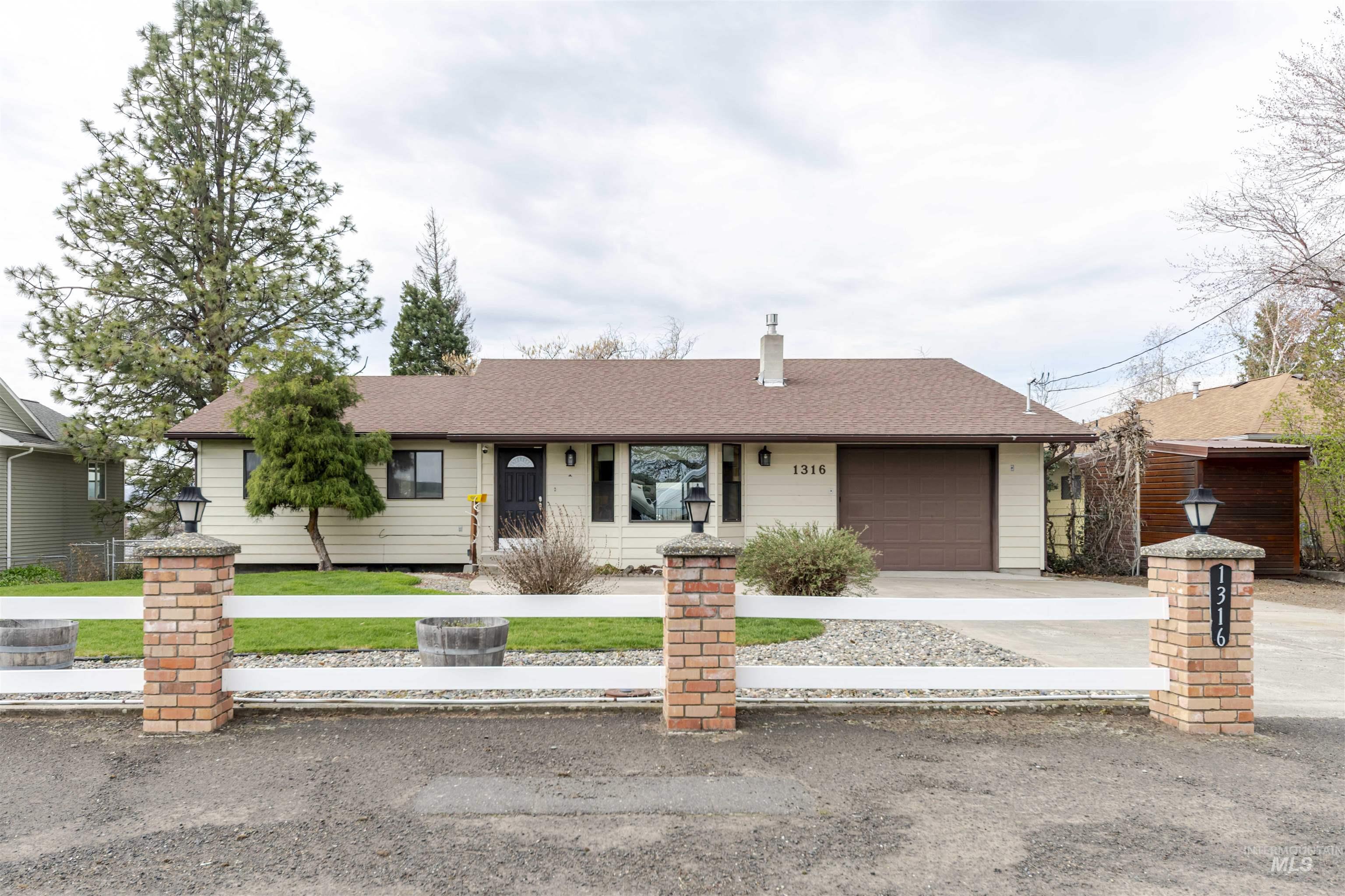 Front of home with an attached garage, concrete driveway, roof with shingles, and a front yard