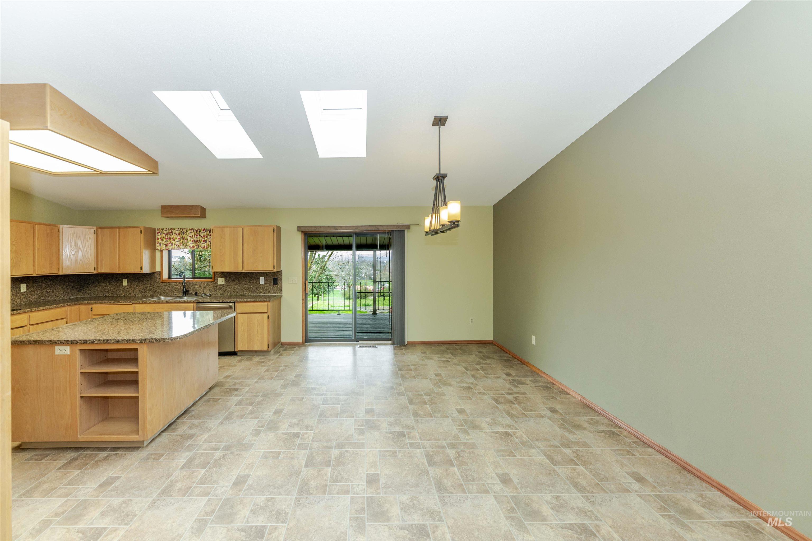 1316 29th Street Lewiston, ID 83501 - Photo 4 of 31 Kitchen featuring a skylight, open shelves, stone finish floors, light stone countertops, and stainless steel dishwasher