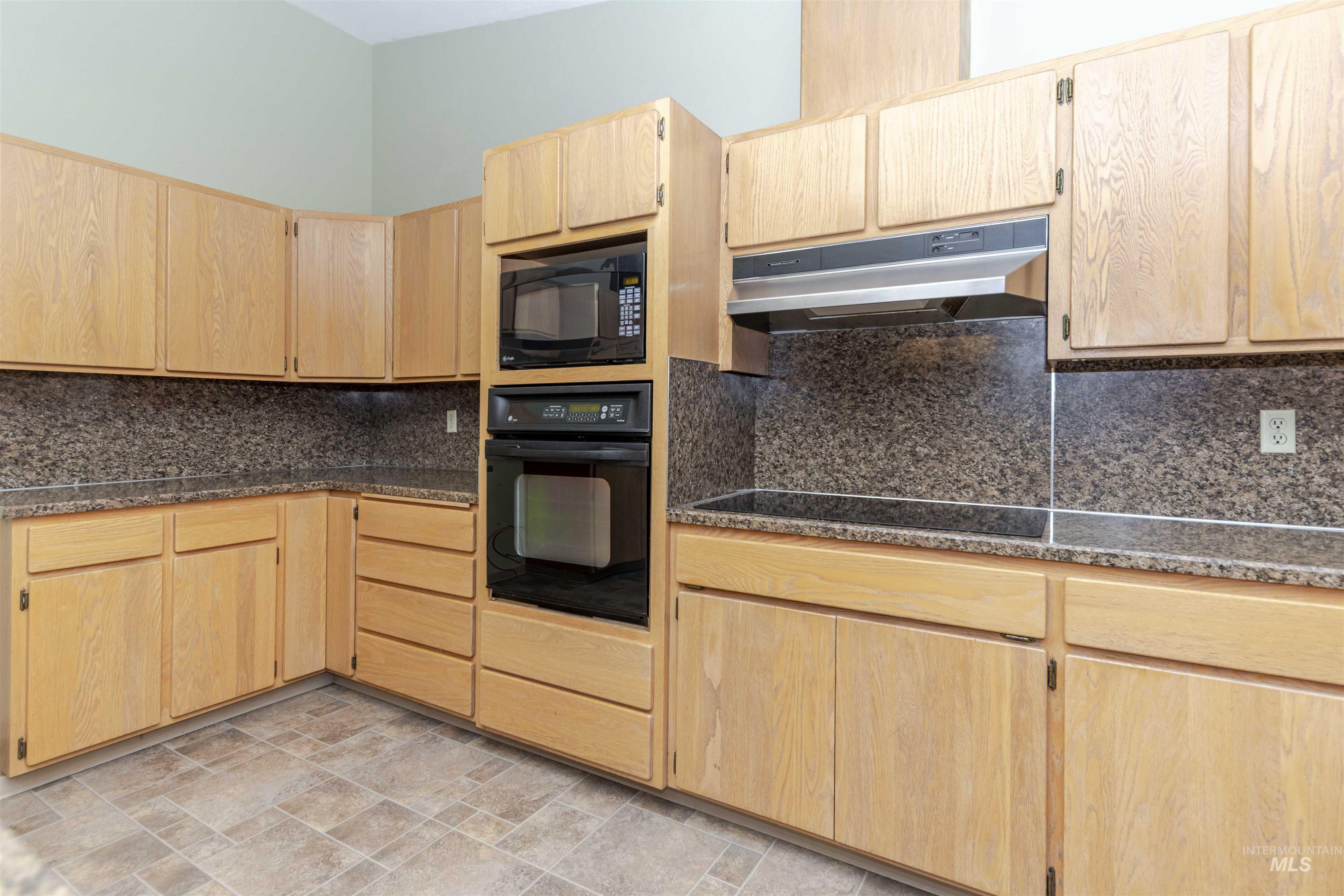 1316 29th Street Lewiston, ID 83501 - Photo 8 of 31 Kitchen featuring light wood finish cabinets, black appliances, backsplash, and stone finish flooring