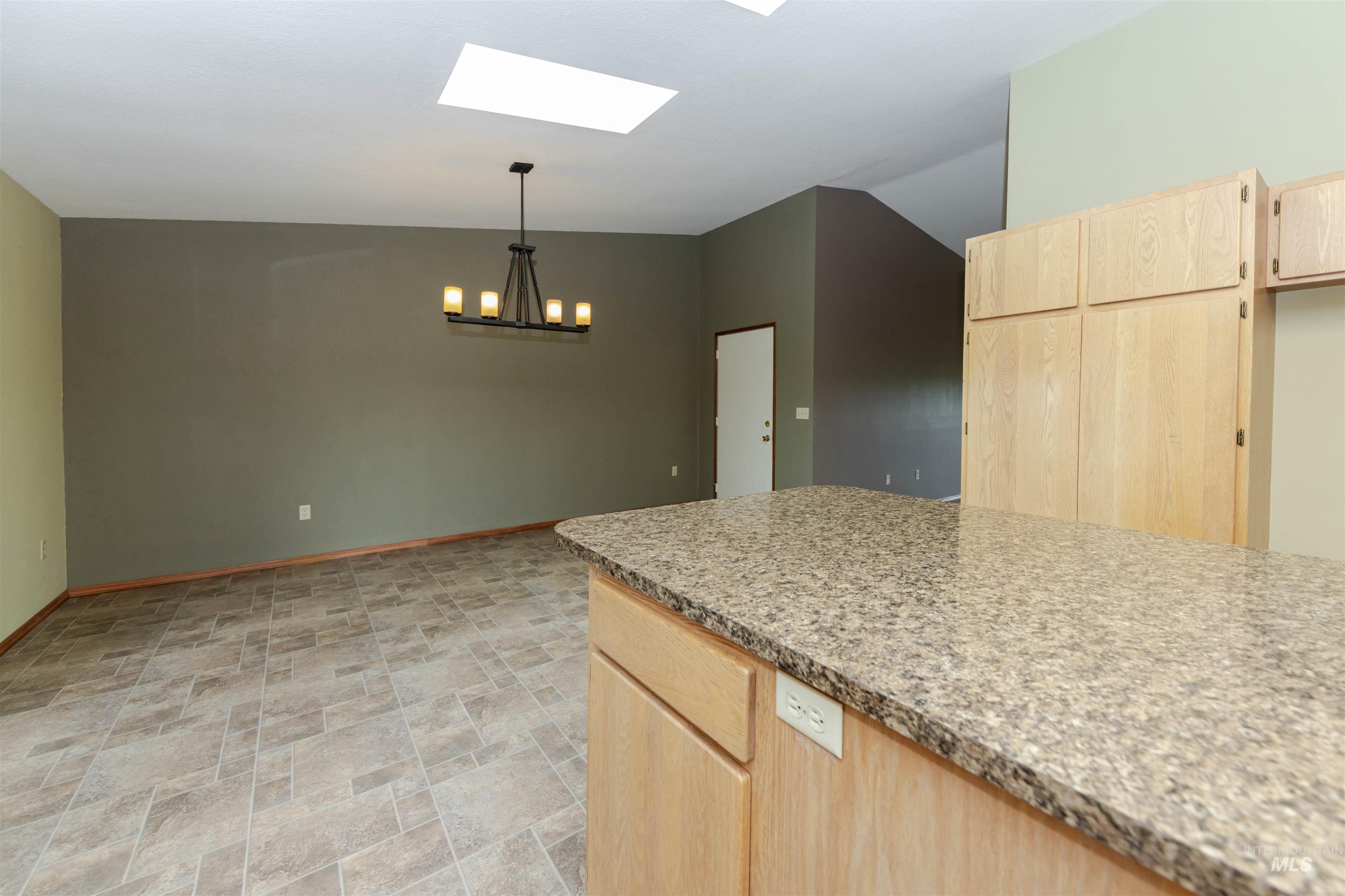 1316 29th Street Lewiston, ID 83501 - Photo 9 of 31 Kitchen with light wood finish cabinets, stone finish flooring, light stone counters, a skylight, and hanging light over dining room