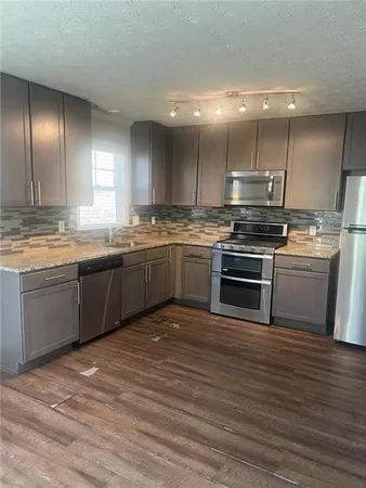 a kitchen with stainless steel appliances granite countertop a sink counter space cabinets and a large window