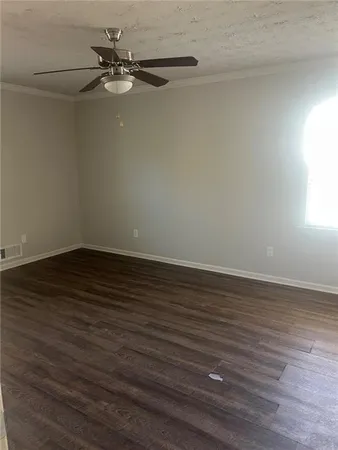 an empty room with wooden floor fan and windows