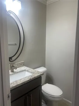 a bathroom with a granite countertop toilet and a sink