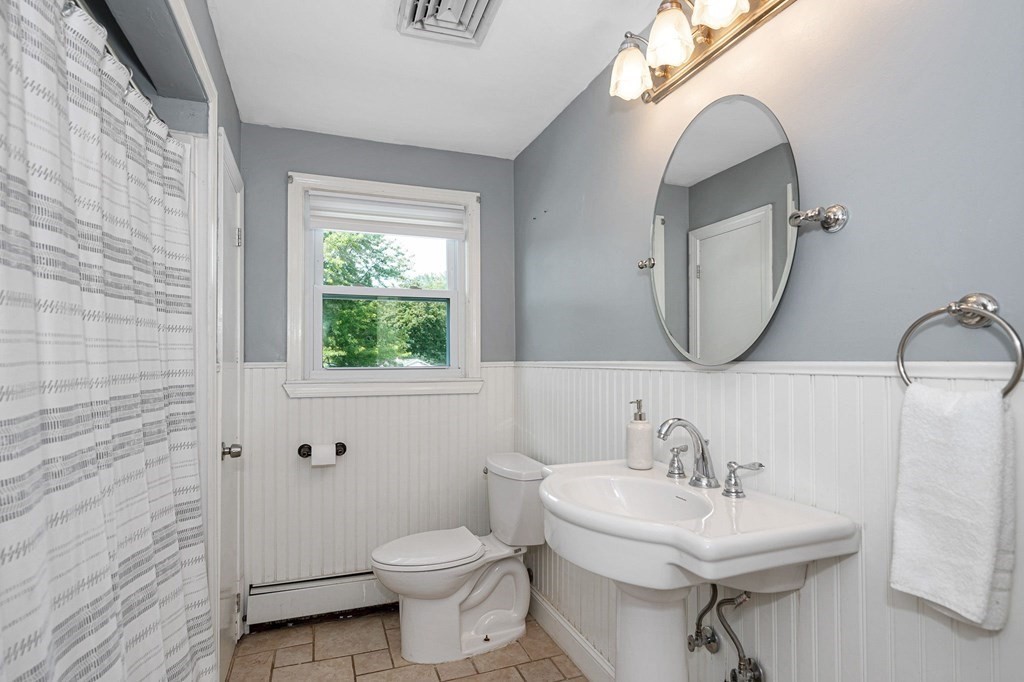 174 Frost Road Tyngsborough, MA 01879 - Photo 7 of 17 a bathroom with a sink a mirror a toilet and a window