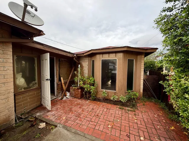 a view of a house with potted plants next to a yard