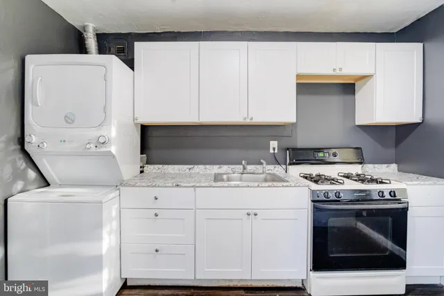 a kitchen with granite countertop a sink a stove and cabinets