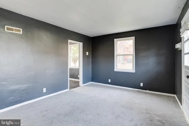 a view of an empty room with window and hardwood floor