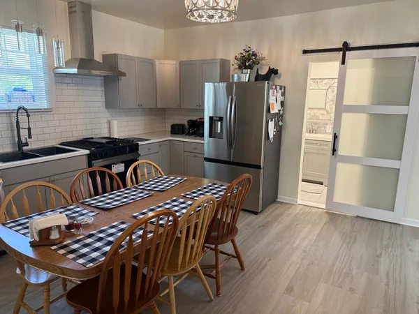 a kitchen with stainless steel appliances a refrigerator a sink a stove a dining table and chairs