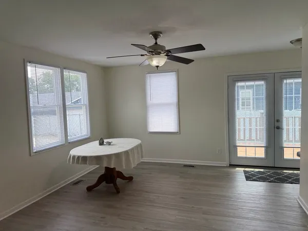 a view of a room with wooden floor a ceiling fan and windows