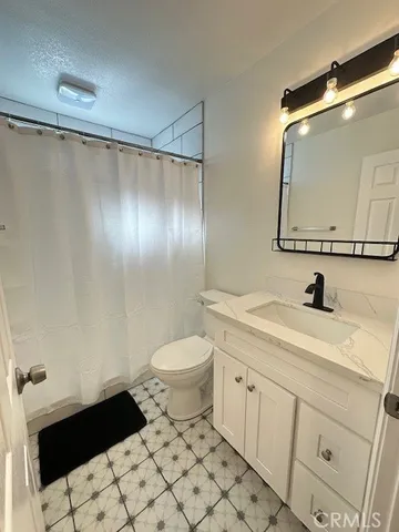 a bathroom with a granite countertop sink mirror vanity and toilet