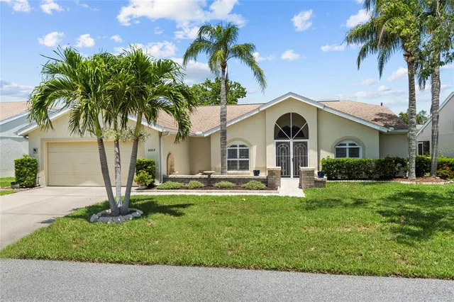 a front view of a house with garden and trees