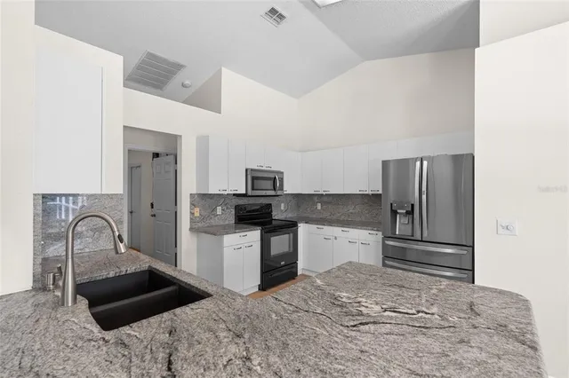 a kitchen with granite countertop a refrigerator and a stove