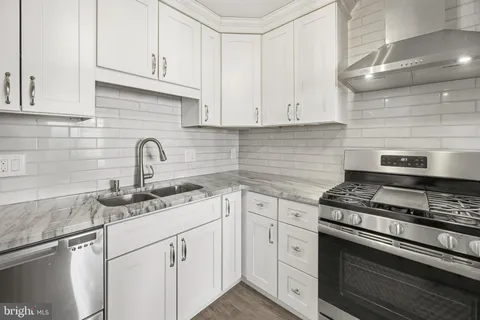 a kitchen with stainless steel appliances a sink a stove a table and chairs