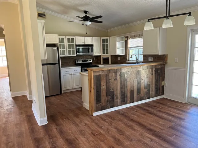 a living room with stainless steel appliances kitchen island granite countertop a refrigerator a stove top oven a sink and dishwasher