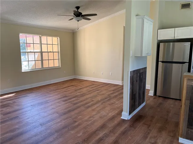 an empty room with wooden floor a ceiling fan and windows