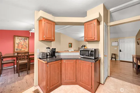 a kitchen with stainless steel appliances granite countertop a stove top oven a sink a dining table and chairs with wooden floor