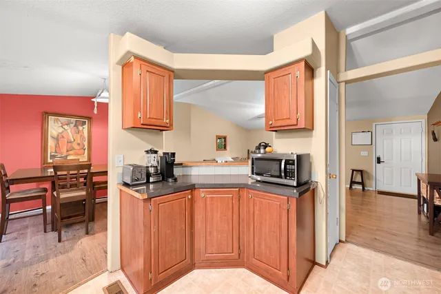 a kitchen with stainless steel appliances granite countertop a stove top oven a sink a dining table and chairs with wooden floor