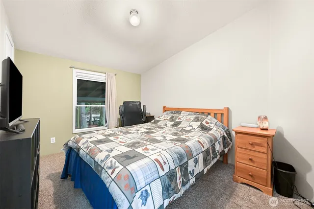 a bedroom with a bed and a flat tv screen on dresser