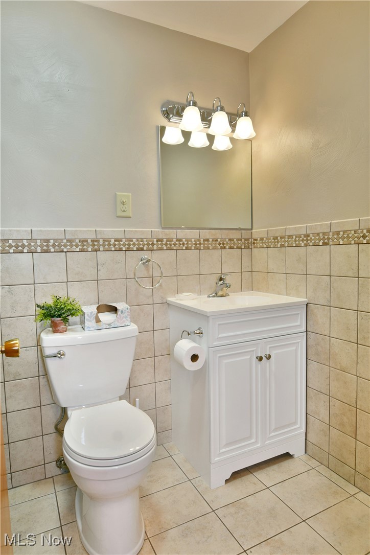 7155 Drake State Line Road Burghill, OH 44404 - Photo 31 of 50 Bathroom featuring vanity, a wainscoted wall, light tile patterned flooring, and tile walls
