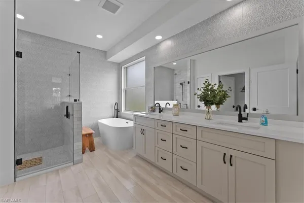 a spacious bathroom with double sink a toilet a shower and a mirror