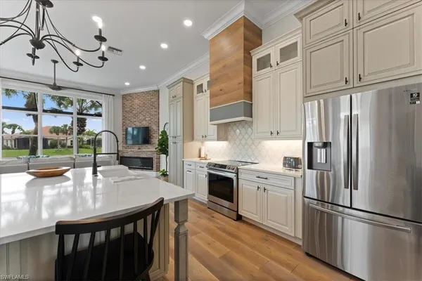 a kitchen with stainless steel appliances granite countertop a refrigerator a sink dishwasher a stove and white cabinets with wooden floor