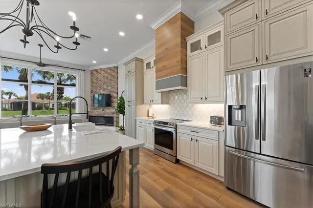 a kitchen with stainless steel appliances granite countertop a refrigerator a sink dishwasher a stove and white cabinets with wooden floor