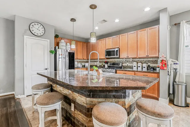a kitchen with stainless steel appliances granite countertop a sink a stove a refrigerator cabinets and chairs