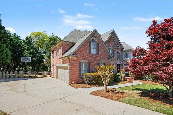 a view of a house with a yard and large tree
