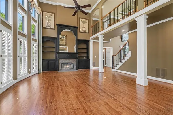 a kitchen with granite countertop a refrigerator a sink dishwasher a stove and white cabinets with wooden floor