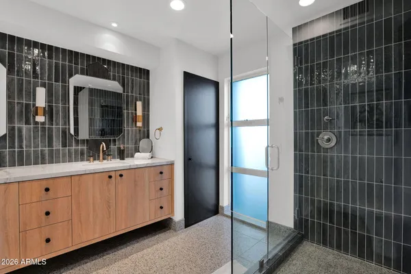 a bathroom with a granite countertop sink a mirror and shower