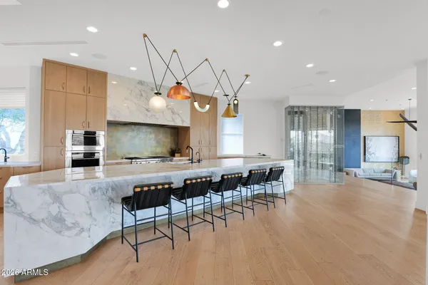 a kitchen with stainless steel appliances granite countertop a stove top oven a sink a dining table and chairs with wooden floor