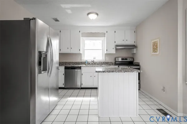 a kitchen with granite countertop white cabinets a refrigerator and a stove