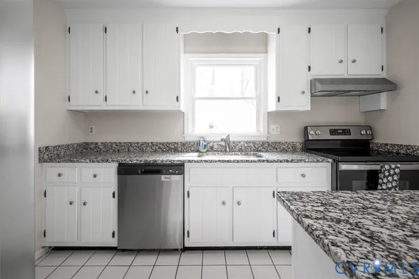 a kitchen with white cabinets granite counter tops and a stove