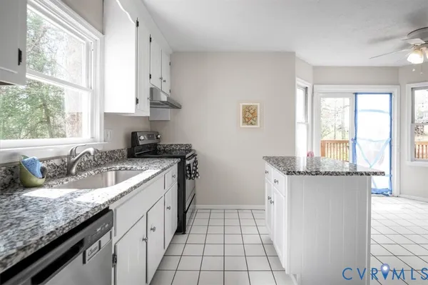 a kitchen with granite countertop a sink a stove and a wooden floors