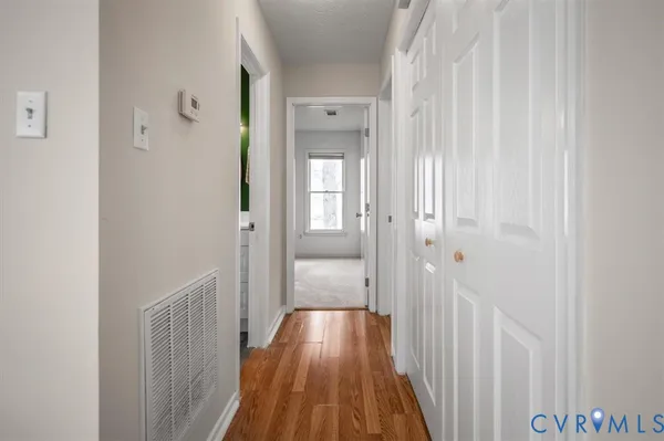 a view of a hallway with wooden floor and a bathroom