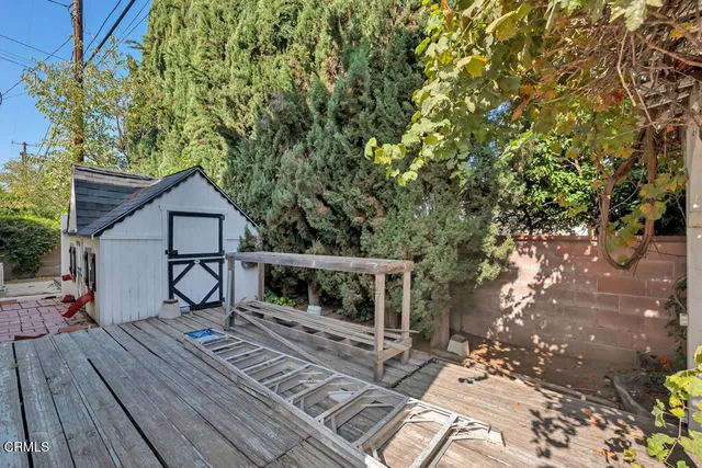 a view of house with wooden deck and a large tree