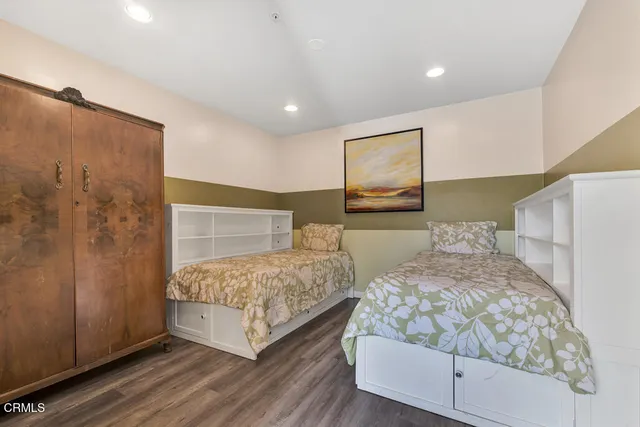 a bedroom with two beds and painting on the wall