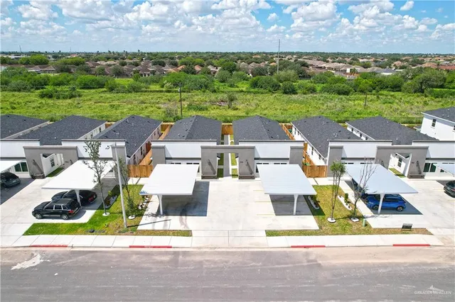 an aerial view of residential houses with outdoor space and parking