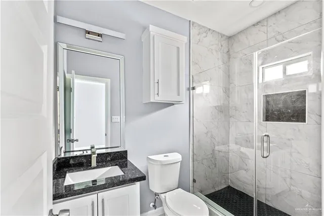 a bathroom with a granite countertop sink toilet and shower