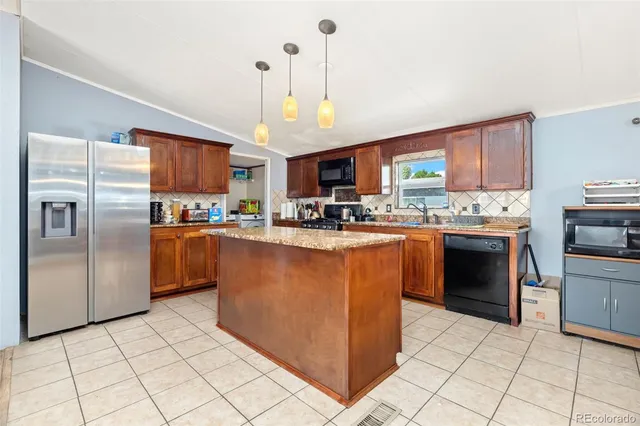 a kitchen with stainless steel appliances granite countertop a stove top oven a refrigerator a sink and a stove