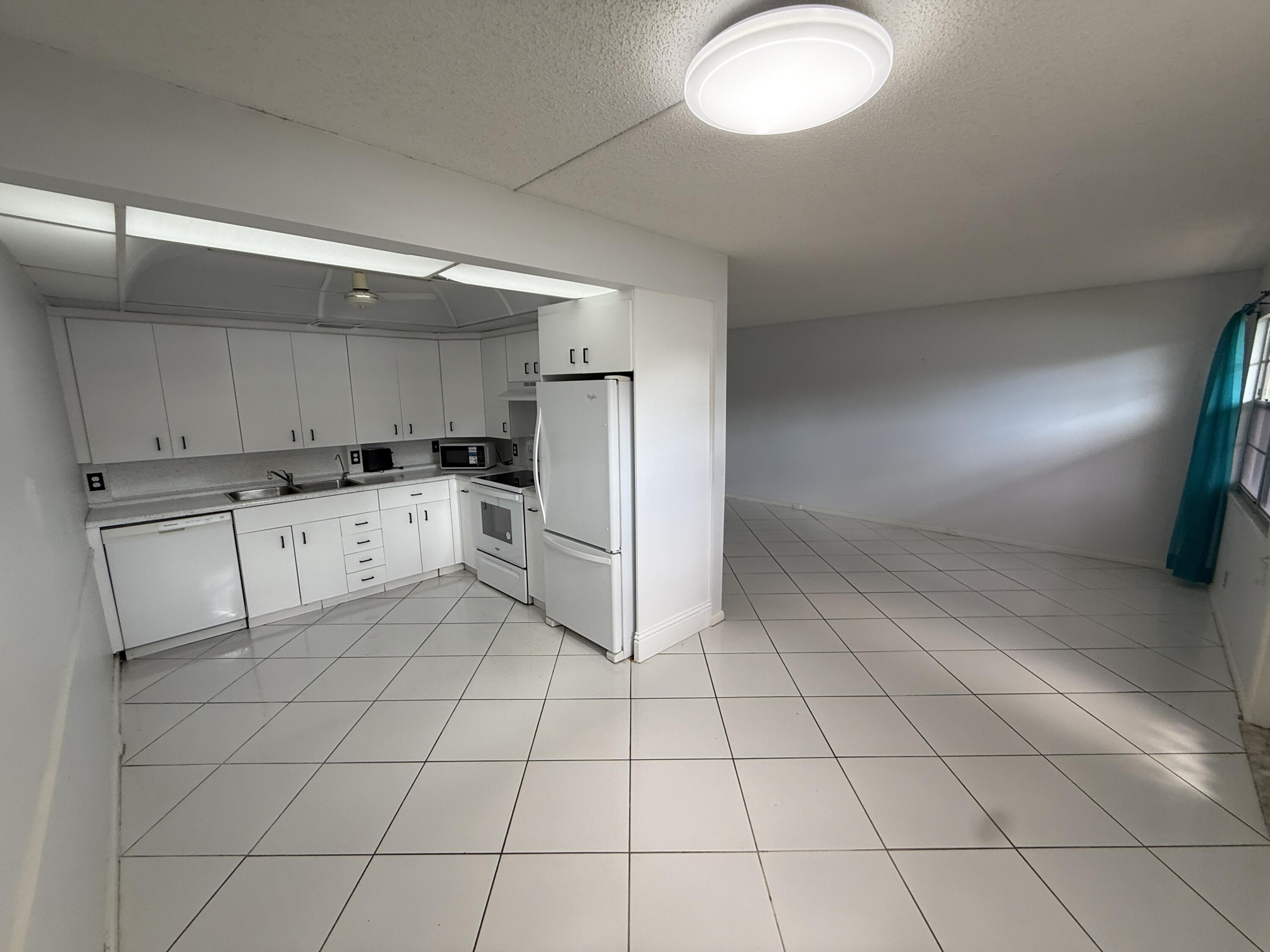 1043 Newcastle A Boca Raton, FL 33434 - Photo 4 of 17 a kitchen with white cabinets a sink and white appliances